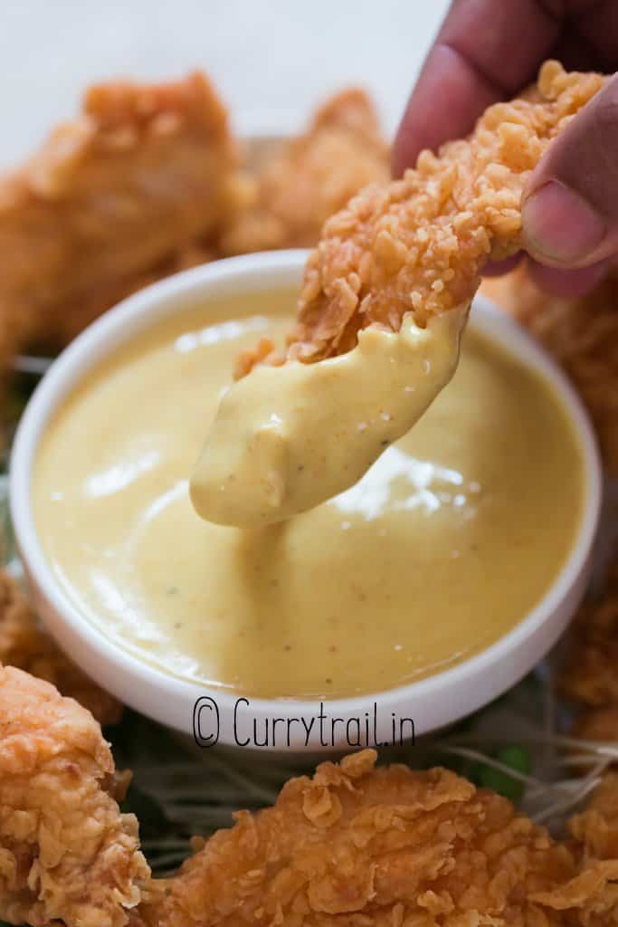 dipping fried chicken in honey mustard sauce