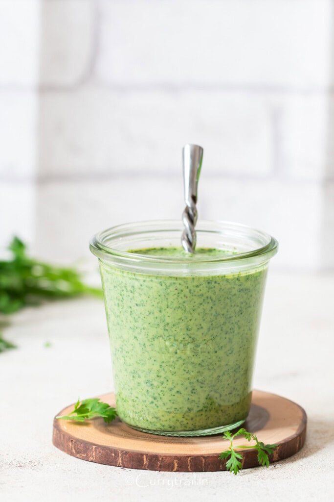 creamy green cilantro sauce in a glass jar.