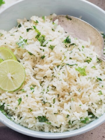 Close-up view of rice with cilantro and lime in a bowl.