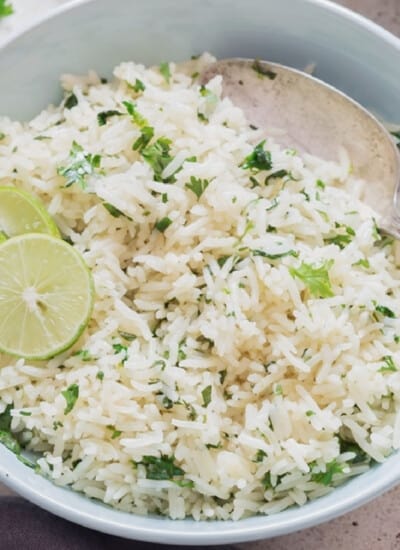 Close-up view of rice with cilantro and lime in a bowl.