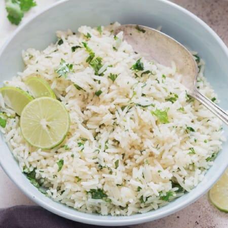 Close-up view of rice with cilantro and lime in a bowl.