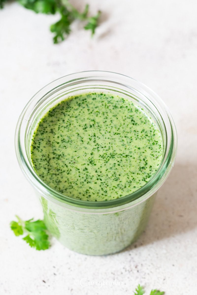 green herb sauce made of cilantro and Greek yogurt in a glass jar.