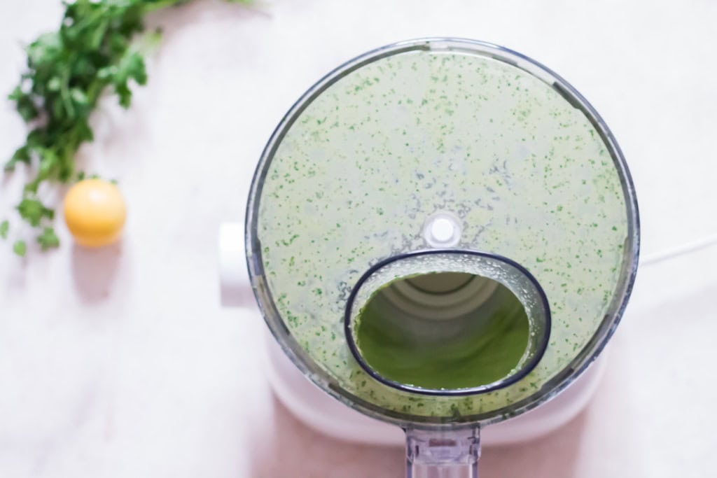 blending fresh herbs, jalapeno, garlic, Greek yogurt, and cumin in a food processor.