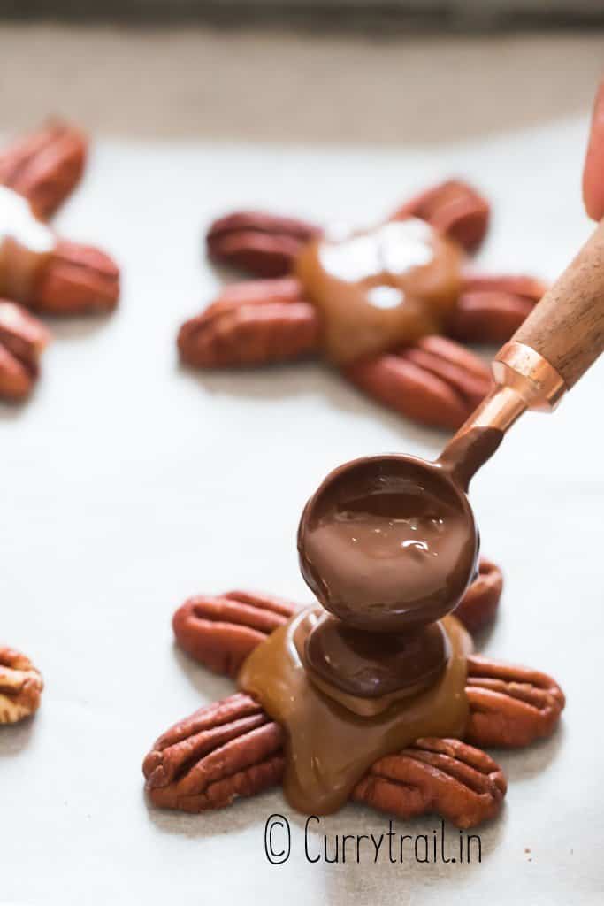 pouring melted chocolate over turtle candy with pecans