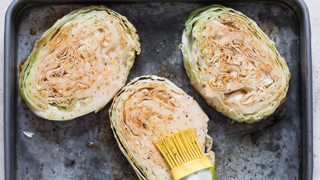 spice rub on green cabbage steaks on a baking tray.