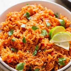Spanish rice in a bowl with lime wedges.