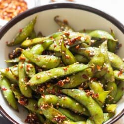 close view of garlic edamame with red chili flakes and toasted sesame seeds