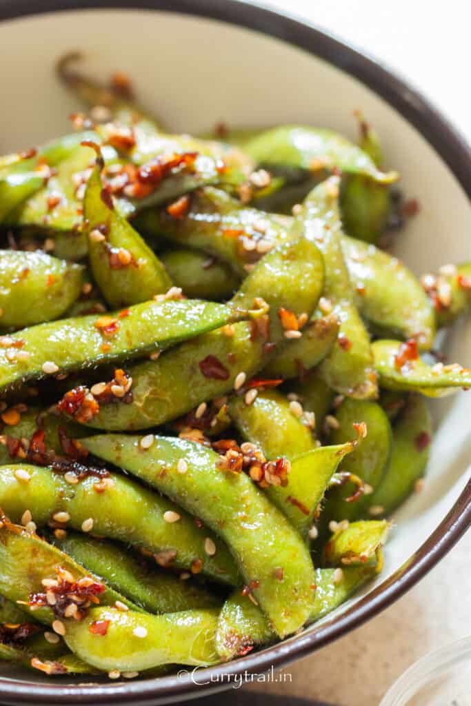 close view of garlic edamame with red chili flakes and toasted sesame seeds