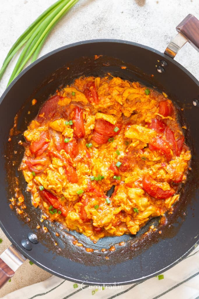 cooking scrambled eggs and tomatoes in wok