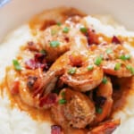 close up view of cajun shrimp on white grits with text overlay