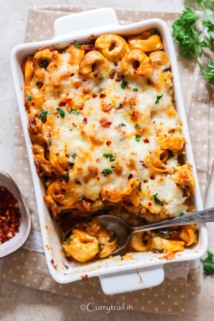 close up view of tortellini casserole with spoon scooping the pasta.