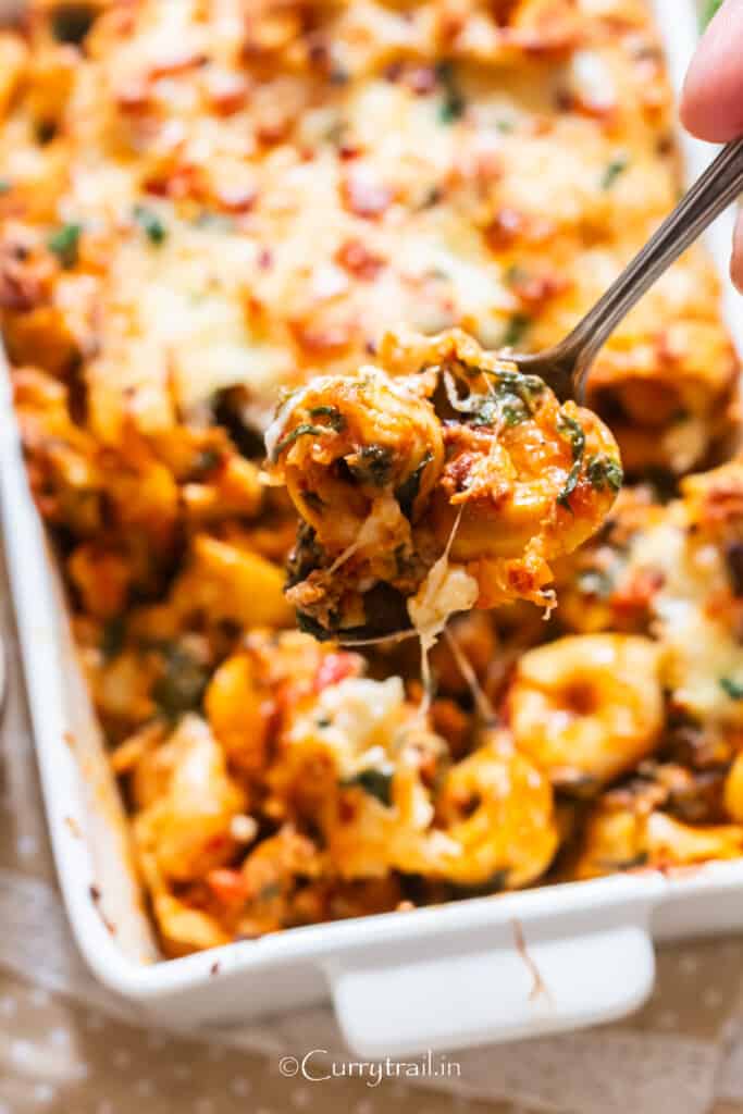 close up view of tortellini casserole with spoon scooping the pasta.