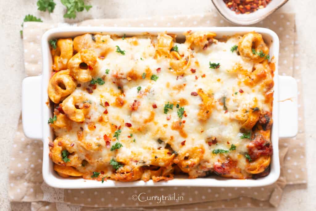 baked cheesy tortellini pasta in a white casserole dish.