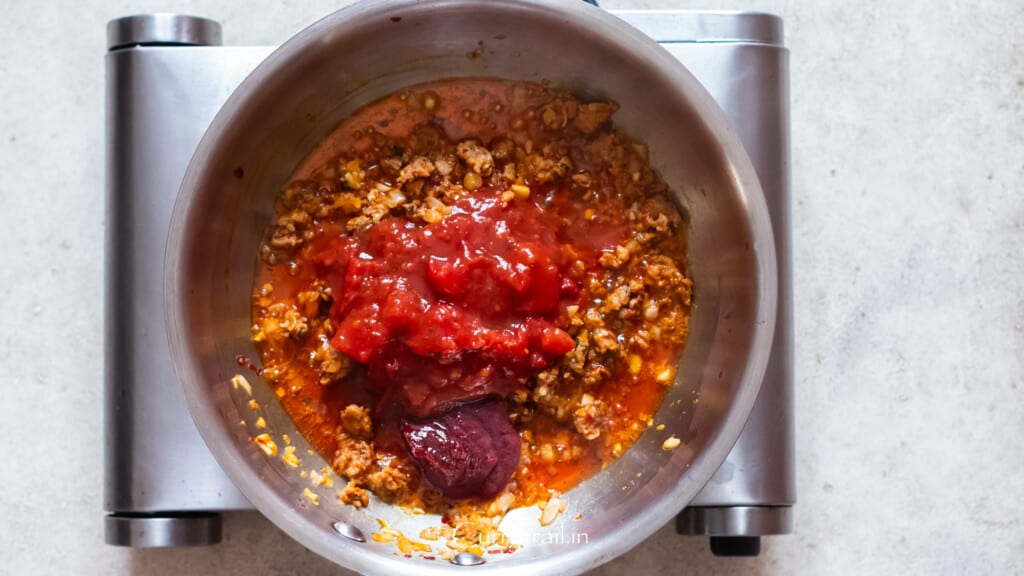 tomato paste and crushed canned tomatoes cooked with Italian sausage in a skillet.