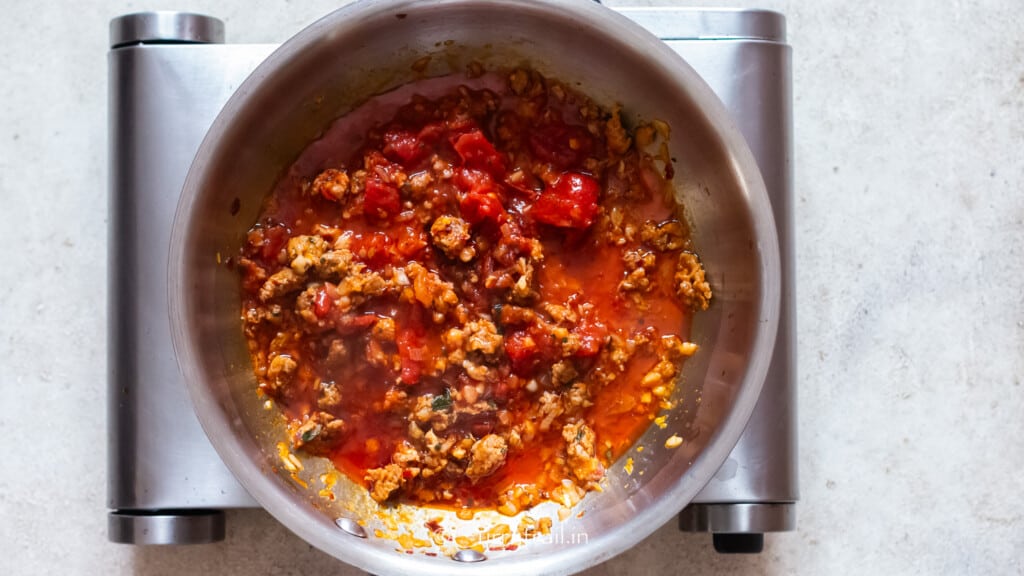 tomato paste and crushed canned tomatoes cooked with Italian sausage in a skillet.
