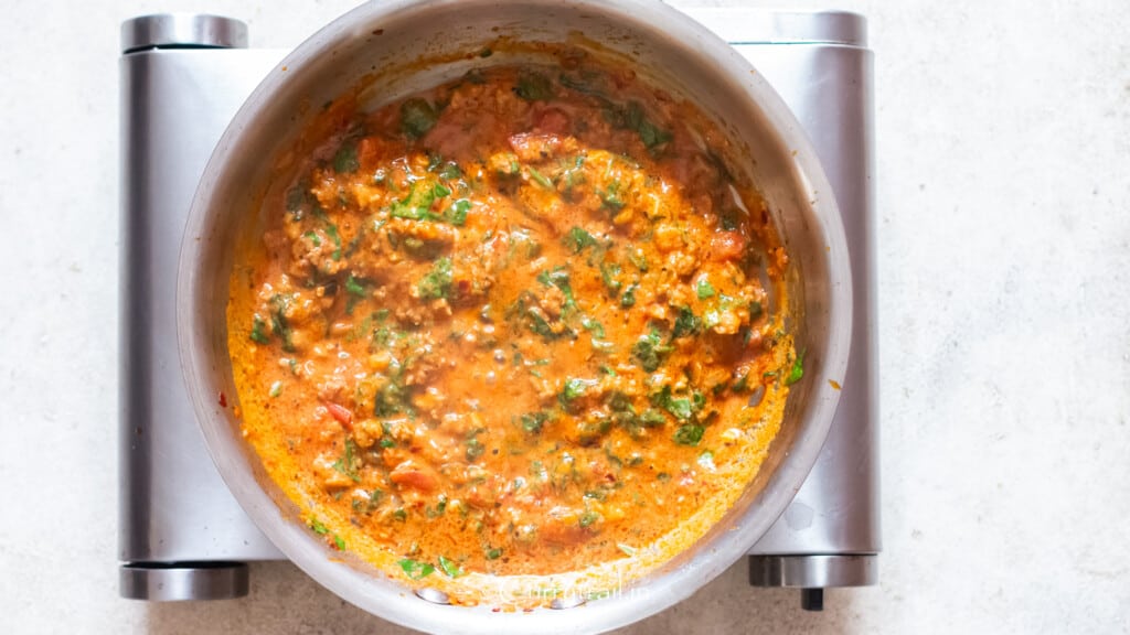 meat sauce with spinach and Italian sausage cooked in a skillet.