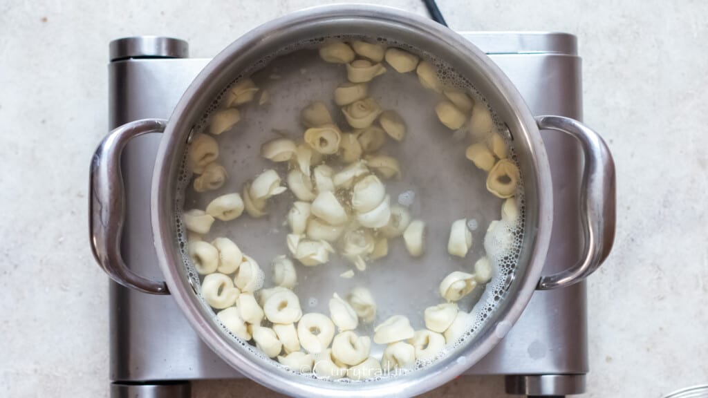 cooking dried tortellini pasta in a boiling pot of water.