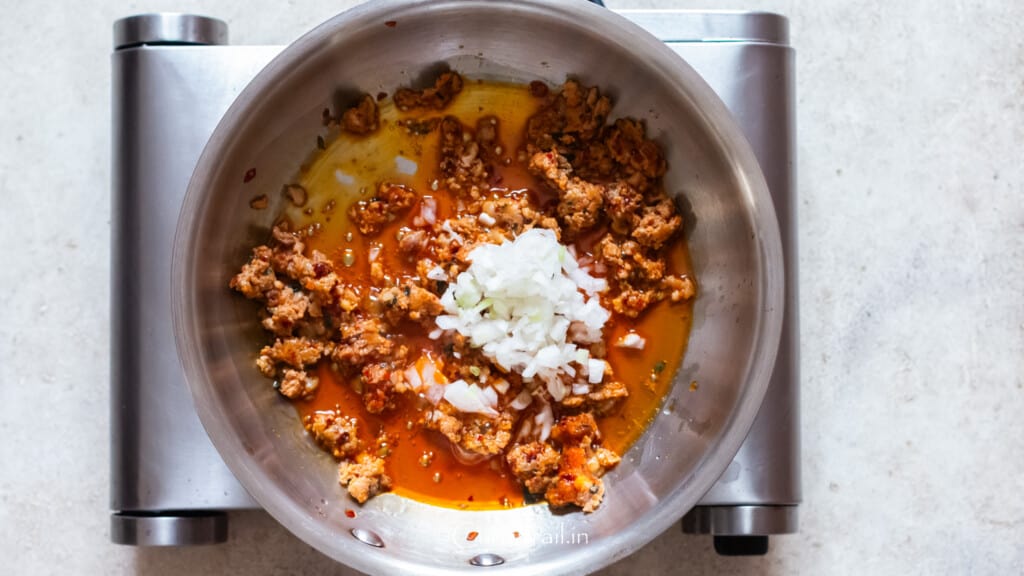 diced white onion cooked with Italian sausage in a skillet.