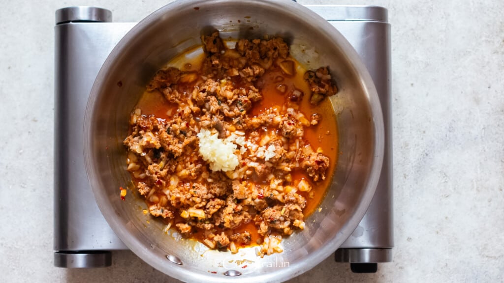 minced garlic cooked with onion and Italian sausage in a skillet.