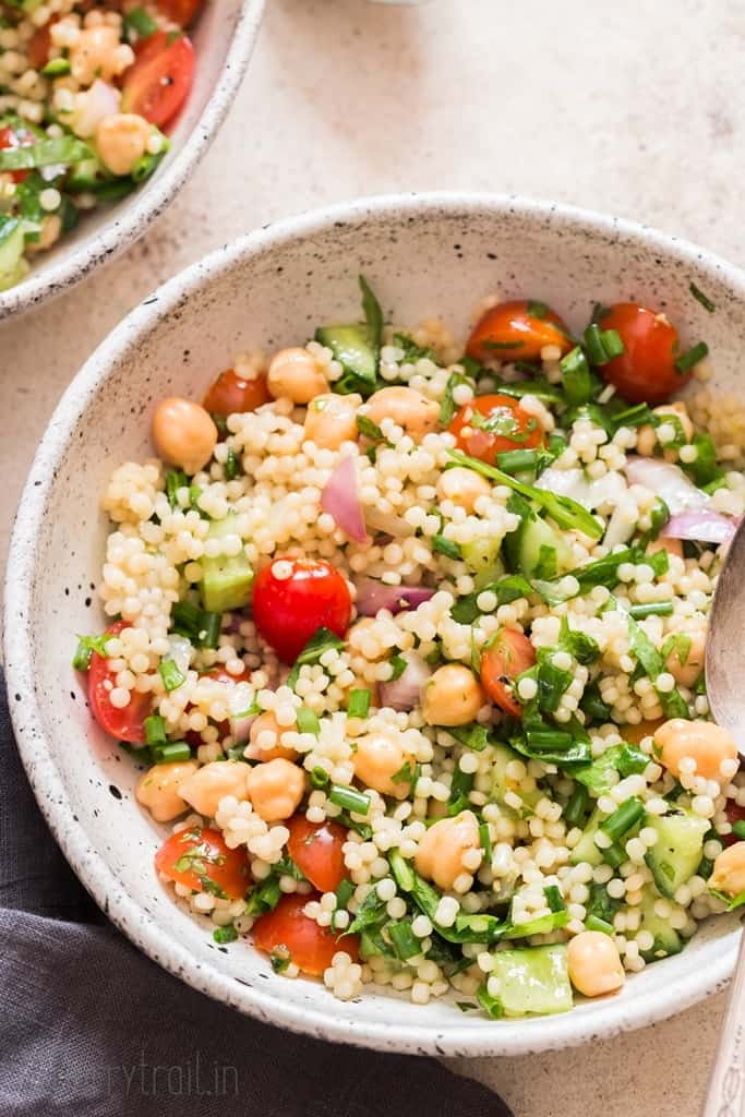 summer pearl couscous salad with chickpeas cherry tomatoes and fresh herbs.