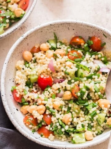 summer pearl couscous salad with chickpeas cherry tomatoes and fresh herbs.