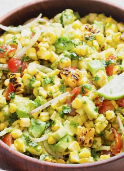 grilled corn and avocado salad in a wooden bowl.