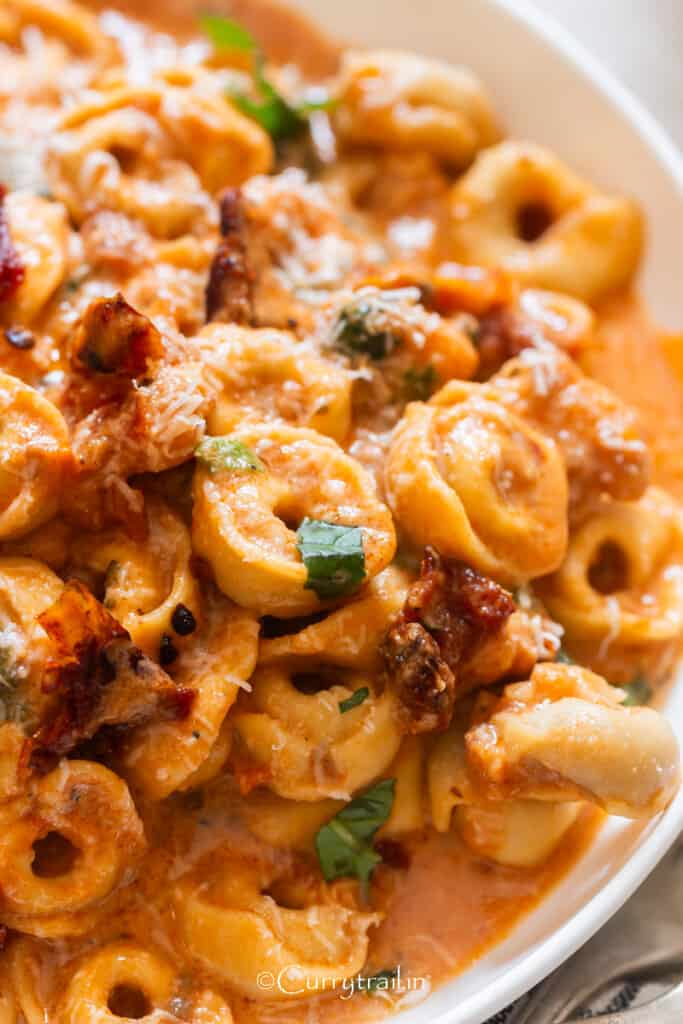 close up view of creamy Marry Me chicken and tortellini pasta on a plate.