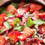 spinach and strawberry salad in a wooden bowl.