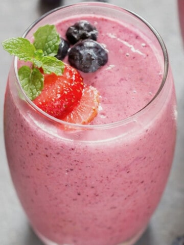 Close-up view of mixed berry smoothie in a glass topped with berries.