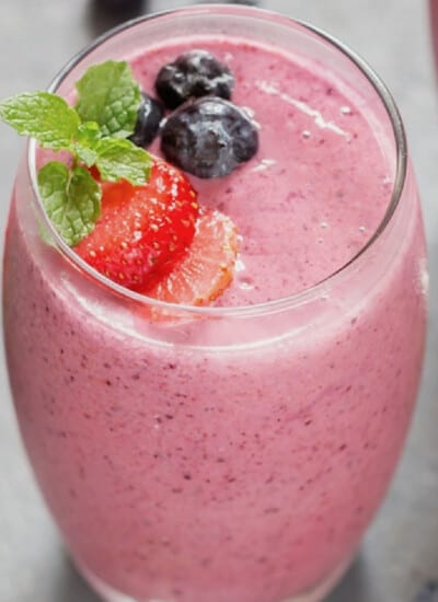 Close-up view of mixed berry smoothie in a glass topped with berries.