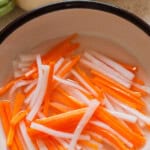 carrot and daikon matchsticks pickled in vinegar with text overlay.