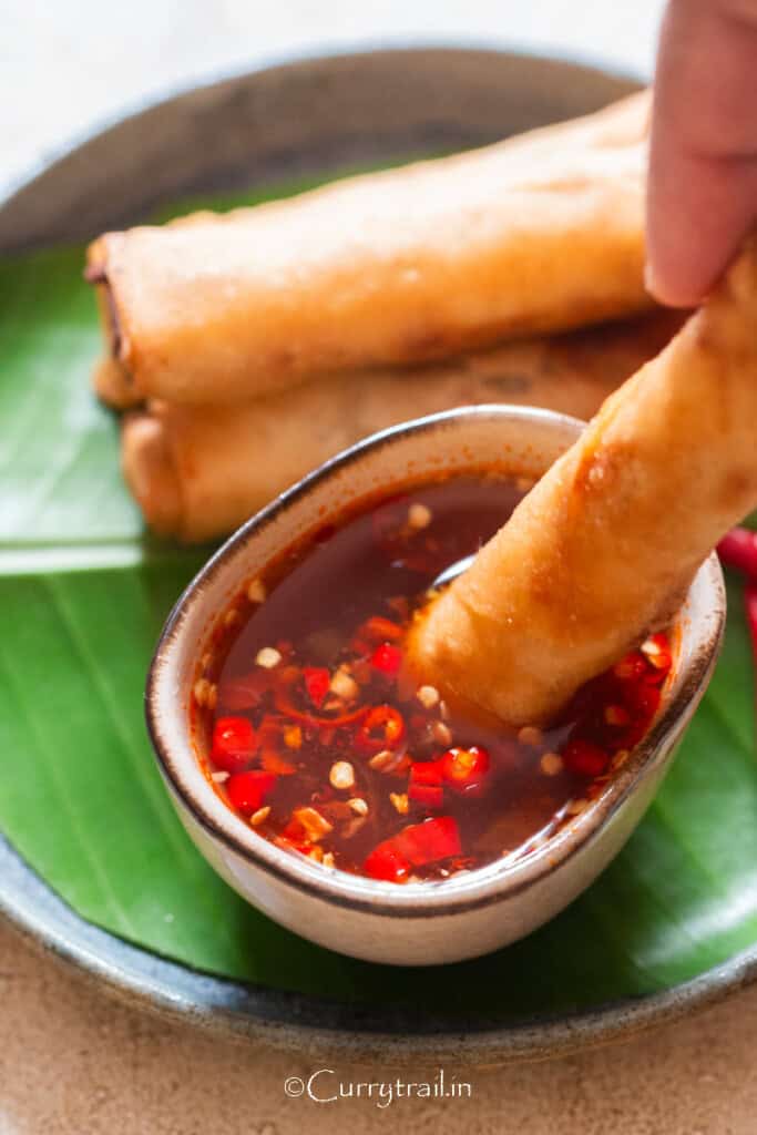 egg roll dipping in Nuoc cham, a Vietnamese dipping sauce.