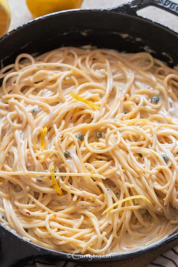 Lemon pasta in a creamy sauce in a cast iron pan.