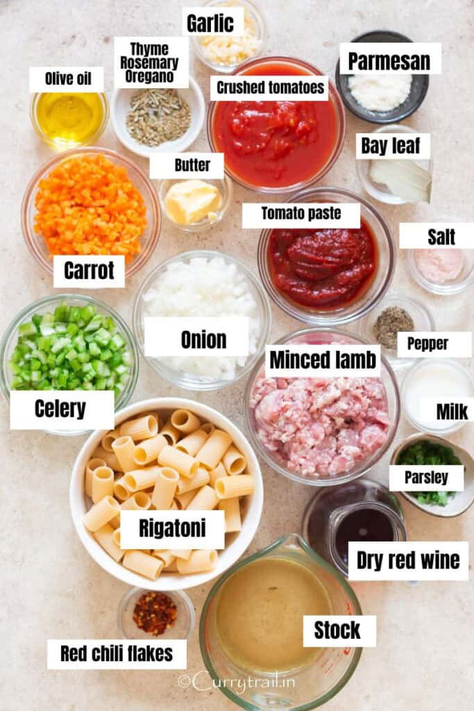 all ingredients for bolognese made using ground lamb arranged on a white table.