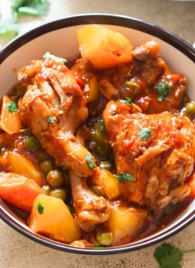 chicken thighs and drumsticks with potatoes and carrots in tomato-based stew.