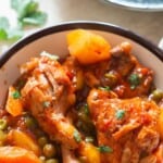 chicken thighs and drumsticks with potatoes and carrots in tomato-based stew.