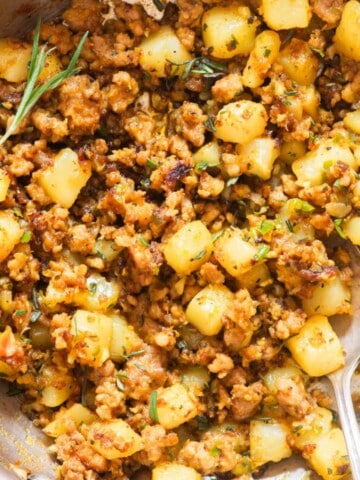 lamb and potatoes in a skillet with fresh rosemary.