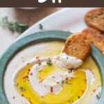 cannellini bean party dip topped with olive oil and fresh thyme, with garlic bread toast on the side.