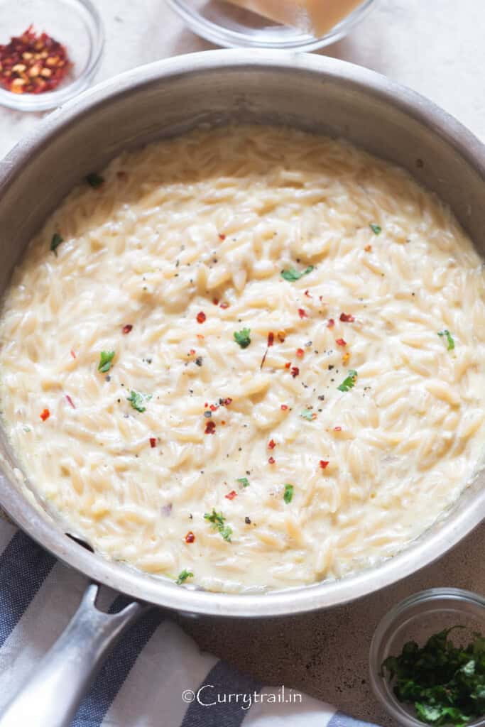 creamy orzo pasta in cooking pan.