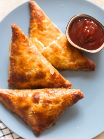 crispy golden corn spinach puffs on a plate with ketchup on the side.