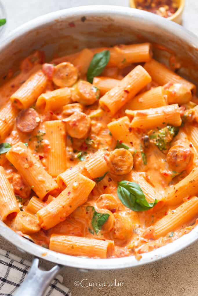 Italian sausage pasta in creamy tomato base sauce in a pan.