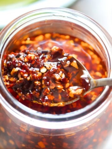 a spoonful of chili oil crisp in a glass jar.