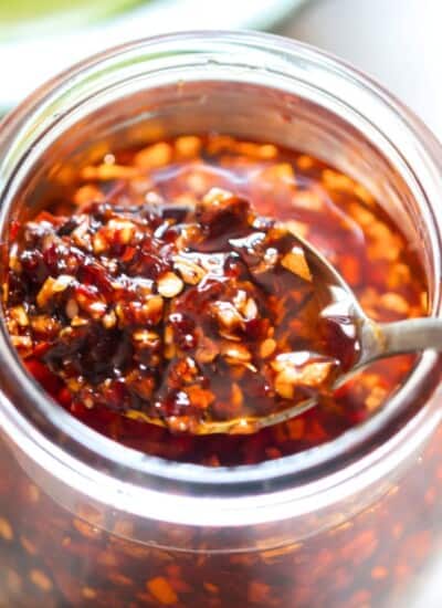 a spoonful of chili oil crisp in a glass jar.