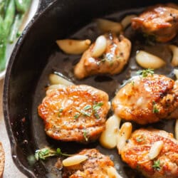 chicken thighs and 40 cloves of garlic cooked in a cast iron pan.