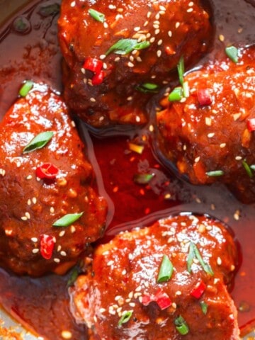 chicken thighs glazed with gochujang sauce and garnished with green onion, sesame seeds and few fresh red chilies.