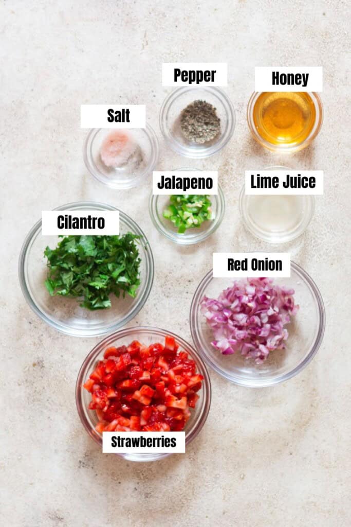 All ingredients for fresh salsa made of strawberries arranged on a table.
