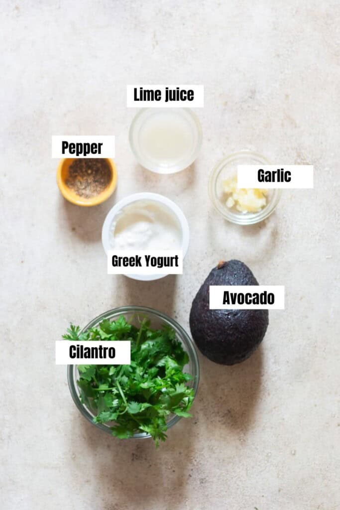 all ingredients for creamy avocado dip on a white table.