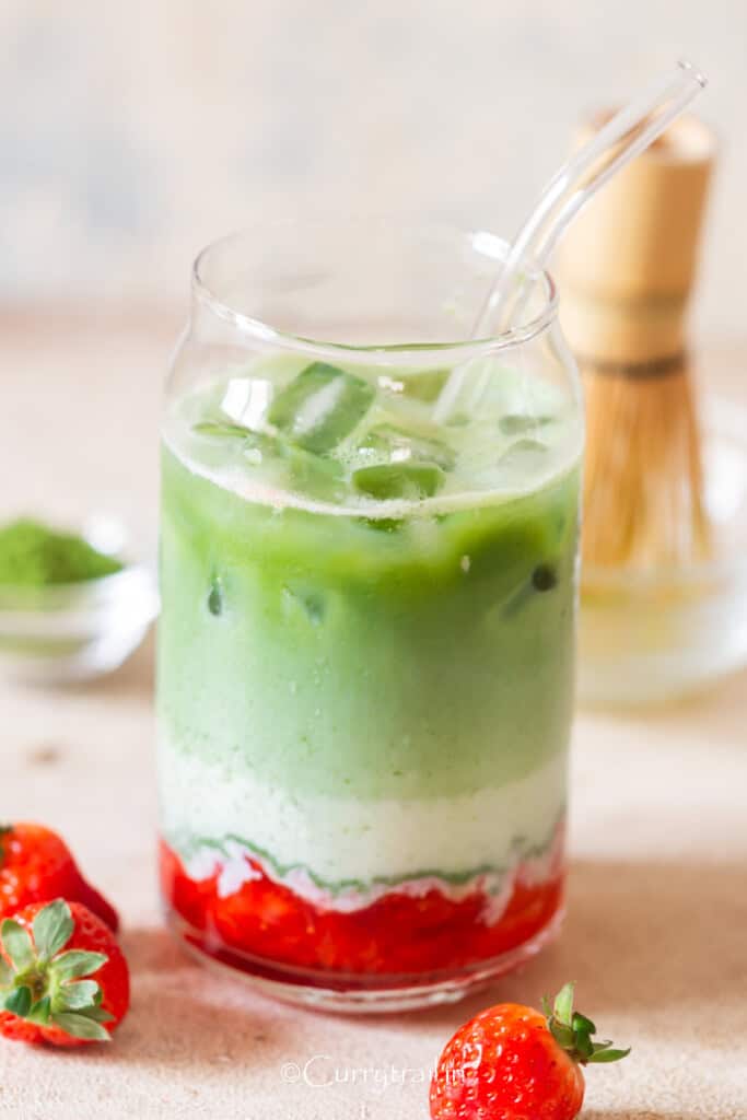 drinking glass with crushed strawberries and matcha tea with milk in 3 layers.
