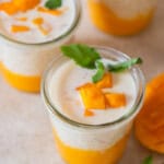 3 glass jars of mango sago served with diced mango and mint leaves.