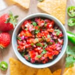 fruit salsa in a bowl with nachos on the side.